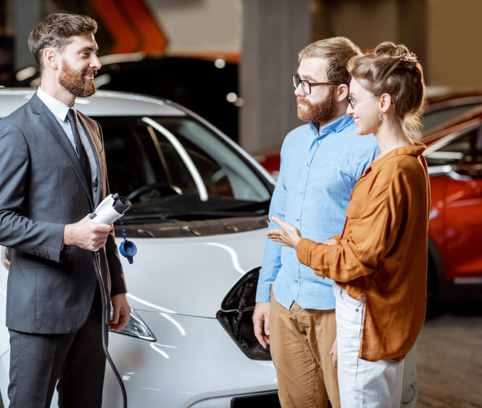 Sales,Manager,Showing,Car,Charging,Station,To,A,Young,Couple,